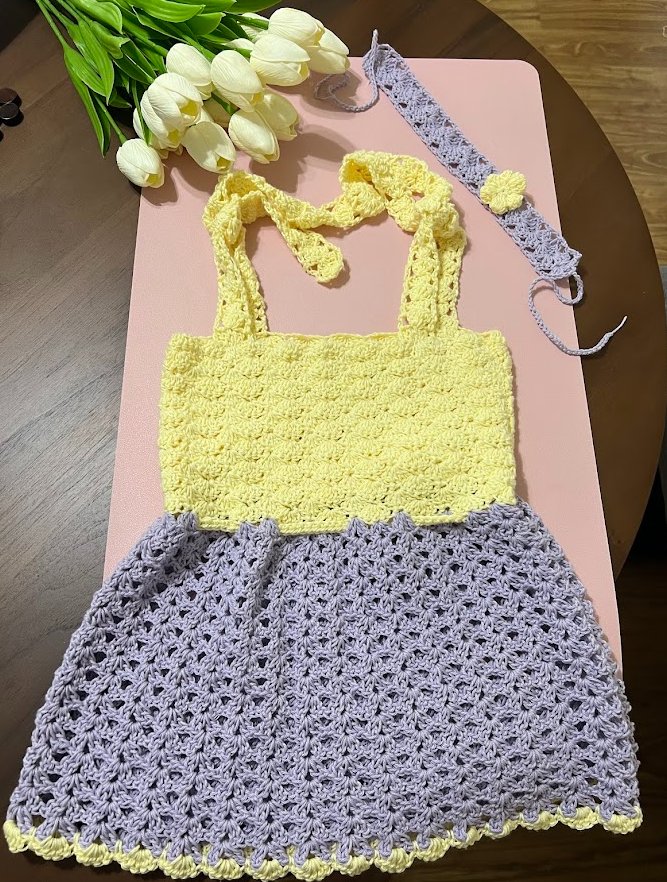 The finished baby dress, laid flat with tulips
