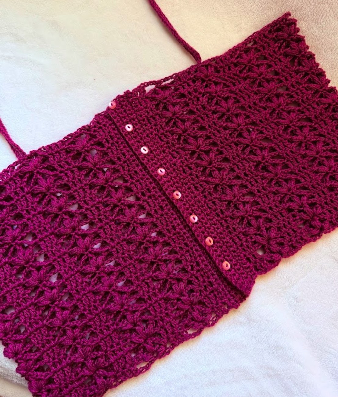 The finished Nazaara top, laid flat with its straps and buttons